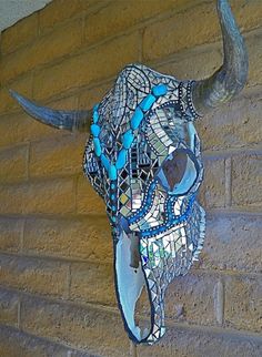 a bull's head is made out of mosaic glass beads and other items hanging on a brick wall