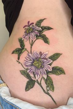 a woman's stomach with flowers and leaves tattooed on the side by tattoo artist