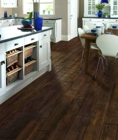 a kitchen filled with lots of white furniture and wooden flooring next to a dining room table