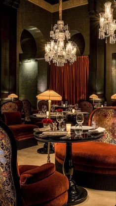 an elegant dining room with chandeliers and red velvet chairs in front of the table