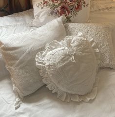 white pillows with ruffles and crocheted edges on a bed in front of a bouquet of flowers