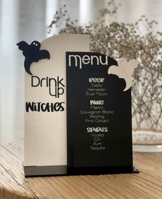 two black and white menus sitting on top of a wooden table next to a vase filled with flowers