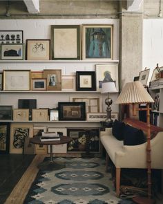 a living room filled with furniture and pictures on the wall next to a table lamp