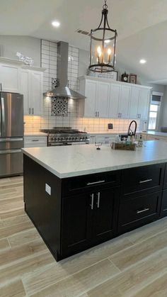 a large kitchen with an island in the middle and stainless steel appliances on both sides