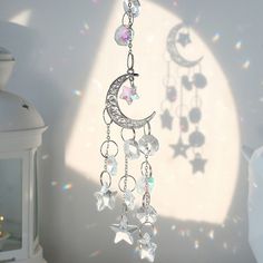 a crescent and stars mobile hanging from a chain in front of a white wall with light shining on it