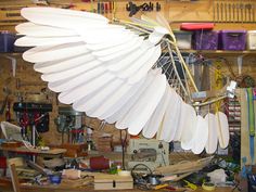 a large white feather sculpture sitting on top of a workbench in a garage