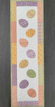 a quilted wall hanging on the side of a wooden door with an egg design