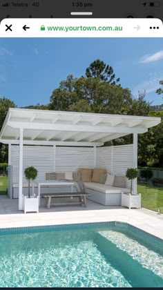 an outdoor living area next to a swimming pool and covered patio with white loungings