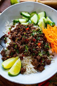 a bowl filled with rice, meat and veggies next to sliced cucumbers