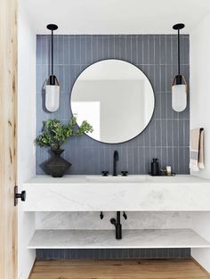 a white sink sitting under a round mirror next to a wall mounted faucet