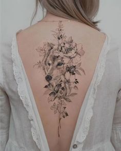 the back of a woman's neck with flowers and a wolf tattoo on it