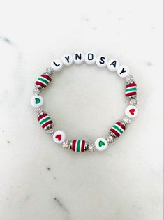 a white bracelet with red, green and white beads that says lyndsay