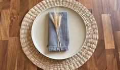 a plate with a napkin and two stalks of wheat on it sitting on a wood floor