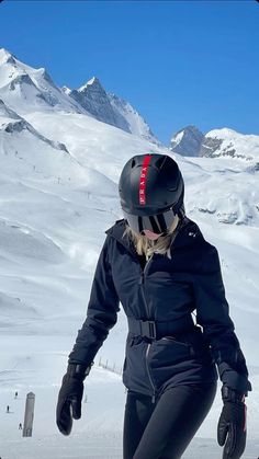 a woman riding skis down the side of a snow covered slope with mountains in the background