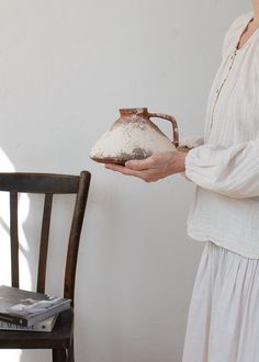 a woman in white holding a brown jug