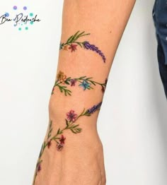 a woman's arm with flowers on it and the wrist is covered in tattoos