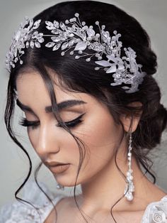 a woman wearing a bridal headpiece with pearls and leaves on the top of her hair