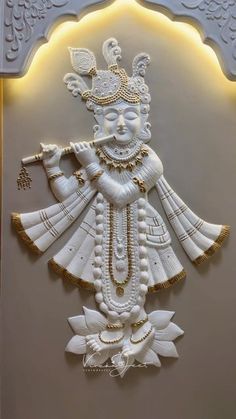 a white and gold wall hanging on the side of a building with a statue in it