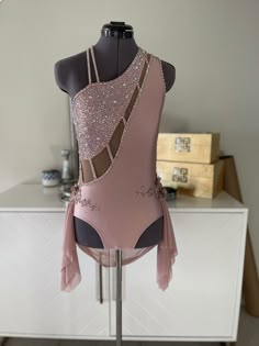 a pink leotard with sequins and tassels on it sitting on a mannequin