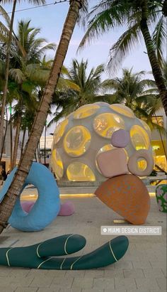 an outdoor sculpture is shown in front of palm trees and other tropical objects on the ground