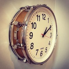 a clock mounted to the side of a wall with two drums on it's sides