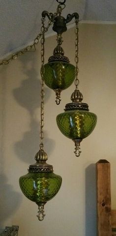 three green glass lamps hanging from a ceiling