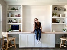 a woman sitting on top of a white desk