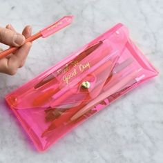 a person is holding a pink pencil in their left hand and it's next to the case