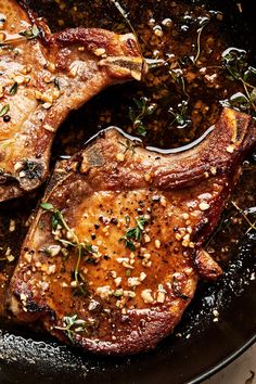 two steaks in a skillet with herbs and seasoning