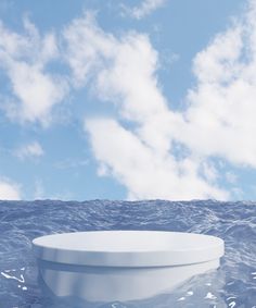 a large white object floating in the middle of the ocean under a cloudy blue sky