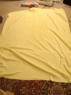 an unmade bed with a yellow blanket on it and a laptop computer sitting on the floor