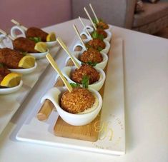 small bowls filled with food sitting on top of a white table next to lemon wedges