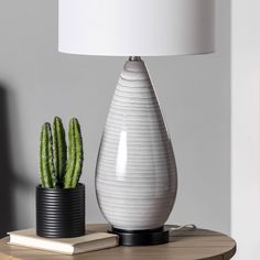 a white vase sitting on top of a table next to a lamp