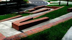 a skateboard park made out of red bricks on the side of a road in front of a building