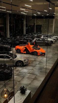 a car showroom filled with lots of different colored sports cars in it's display cases