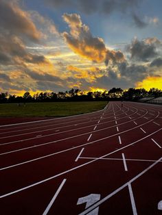 the sun is setting over a running track