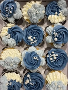 blue and white cupcakes are arranged in a box