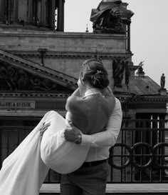 a man and woman embracing each other in front of a building