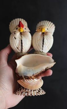 two small shells in the palm of someone's hand, with one shell shaped like a chicken