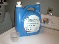 a blue jug sitting on top of a dryer next to a glass and bottle