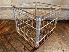 a metal basket sitting on top of a wooden floor