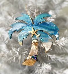 a christmas ornament with a palm tree and starfish hanging from it's side