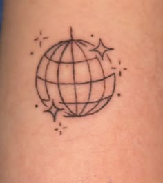 a black and white photo of a small globe tattoo on the leg, with stars around it