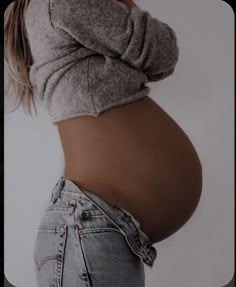 a pregnant woman's stomach is shown with her hands on her hips and the bottom half of her body visible