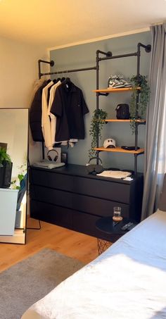 a bedroom with a bed, dresser and clothes rack