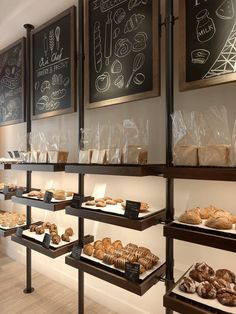 the bakery is stocked with breads and pastries for sale on shelves in front of chalkboard menus