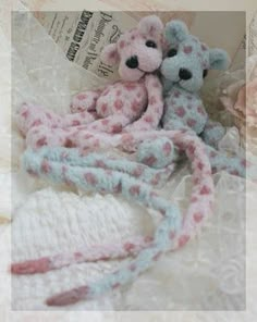 two stuffed animals are laying next to each other on a lace doily covered surface