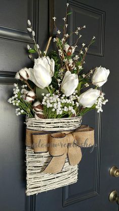 a basket with flowers hanging on the front door