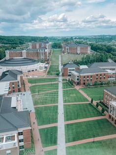 an aerial view of a college campus with green grass and buildings in the background on a cloudy day