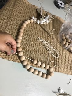 someone is making a bead necklace out of wood beads on a table with other items